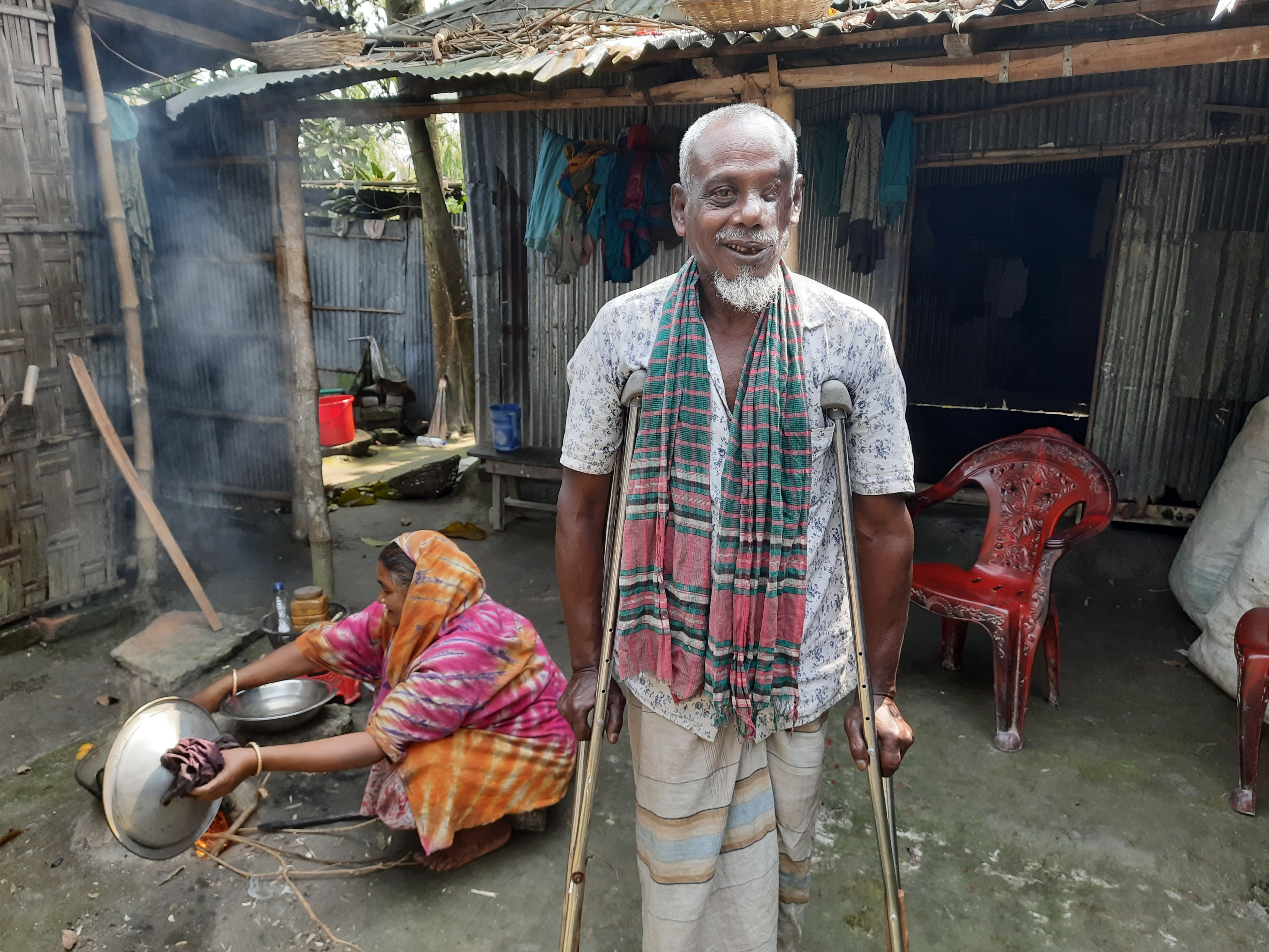 Yousuf smiling in his while his family member cooks behind him.