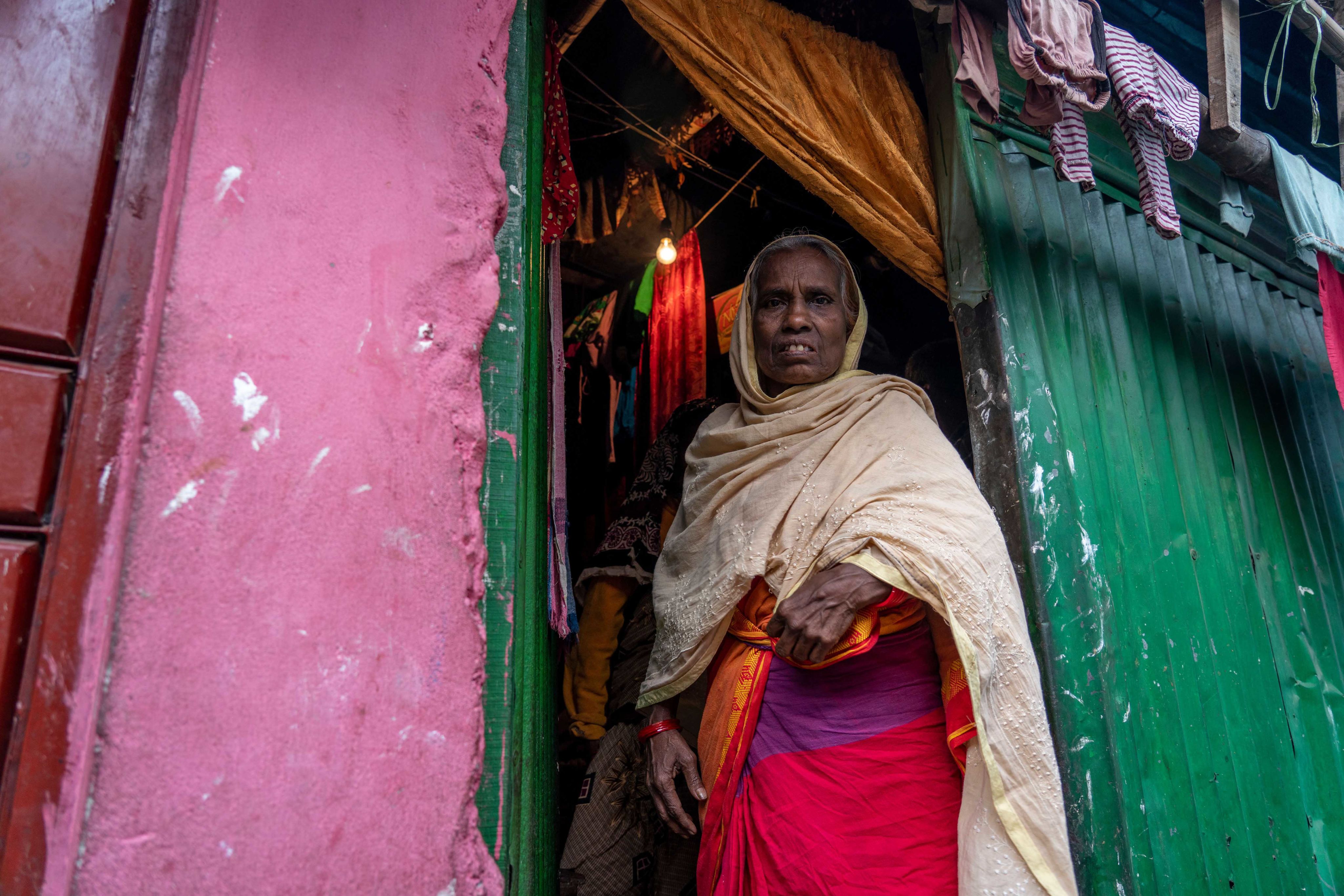Hasina stands in the doorway to her home.