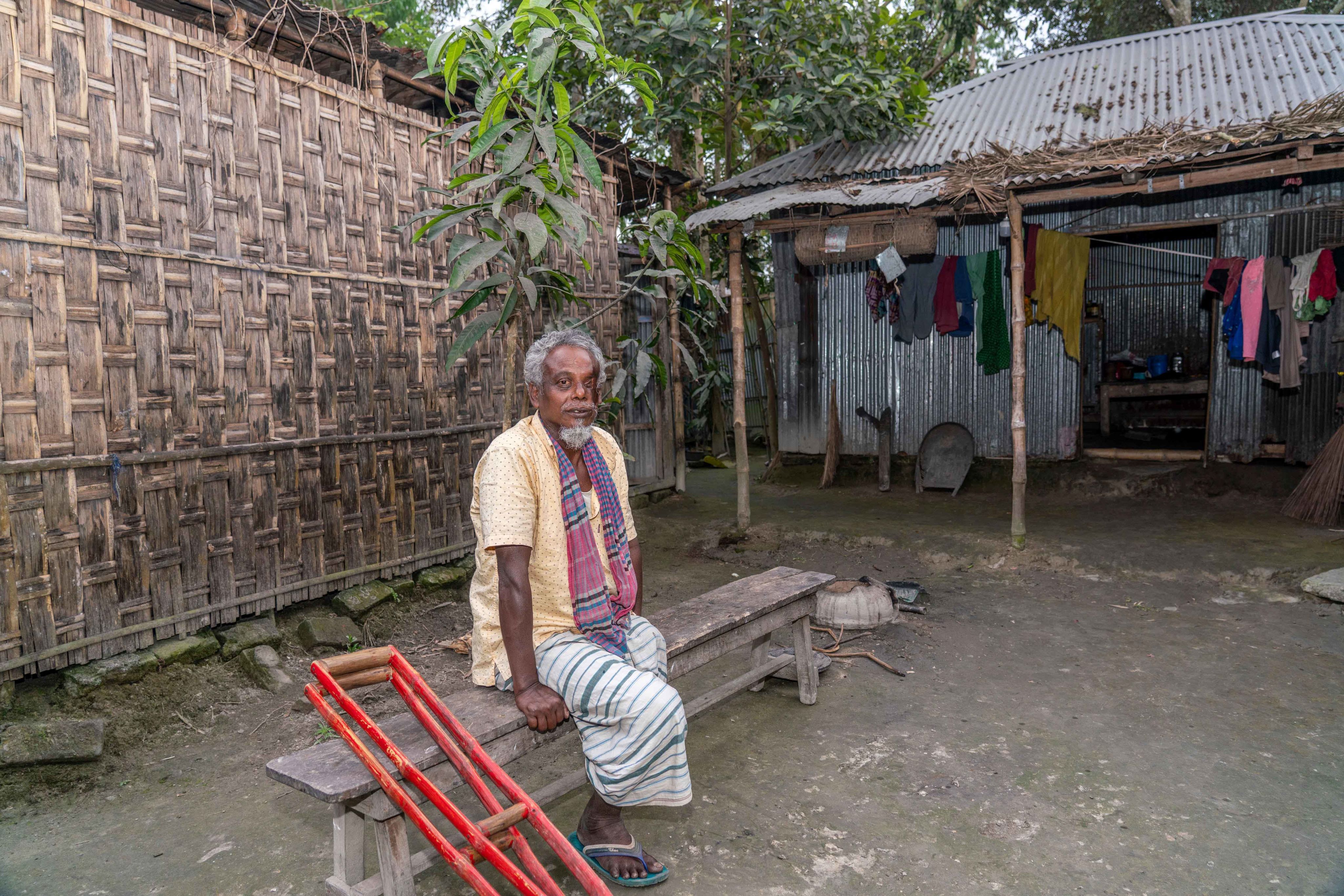 Yousuf sits on a bench outside his house